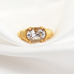 Anillo clásico de titanio dorado con piedra ovalada y banda acanalada en seda