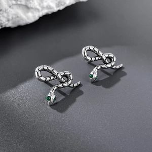 Detailed macro view of snake stud earring with green gemstone eyes and scaled texture
