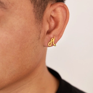 Macro view of a gold snake earring with green gemstone eyes on a person ear