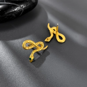 Macro detail of golden snake stud earrings with green zircon eyes and scale texture