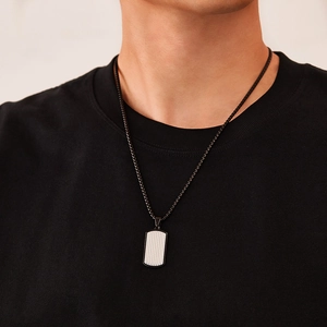 Détail macro du collier plaque d'identité noire pour homme avec insert argenté sur modèle