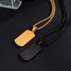Détail de pendentifs rectangulaires mats dorés et noirs sur fond de cuir noir texturé