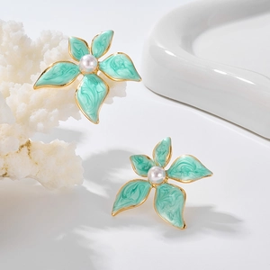 Détail de boucles d'oreilles fleurs vert clair avec pétales émaillés et perle centrale