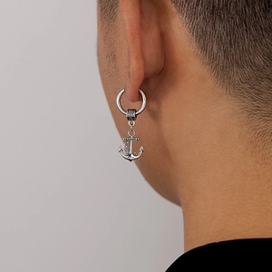 Gros plan d'une boucle d'oreille ancre en acier inoxydable portée par un mannequin homme