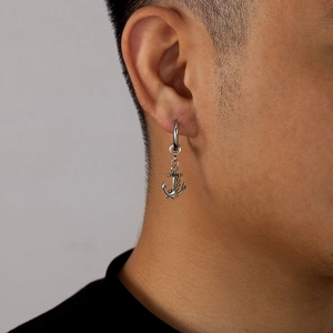 Gros plan d'une boucle d'oreille ancre en acier inoxydable argenté sur un homme