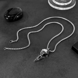 Macro shot of gothic bird skull pendant in vintage silver steel on dark stone base