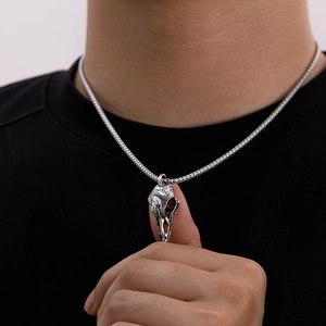 Detailed close-up of a vintage stainless steel bird skull pendant with intricate engravings