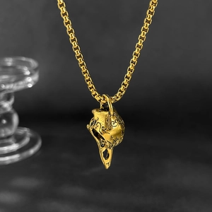 Macro shot of gold bird skull pendant with vintage texture on a venetian chain