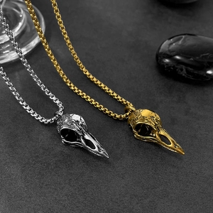 Macro shot of gothic bird skull pendants in silver and gold with intricate textures