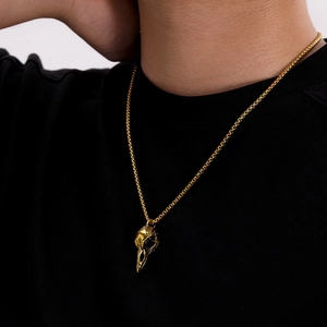 Detailed close-up of a golden raven skull pendant necklace on a black shirt for men