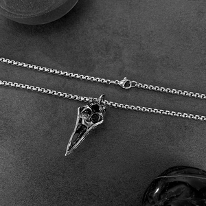 Macro view of gothic raven skull pendant with vintage texture and steel box chain