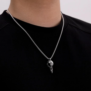 Detailed close-up of a silver bird skull pendant on a box chain for men's punk style