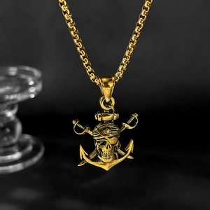Détail macro du pendentif tête de mort pirate et ancre sur une chaîne à maillons dorés