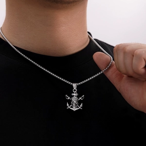 Gros plan d'un pendentif ancre de pirate argenté avec crâne et épées croisées