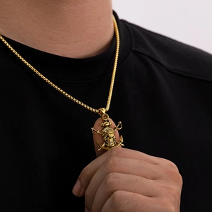 Gros plan du pendentif crâne de pirate doré avec ancres croisées sur chaîne box pour homme