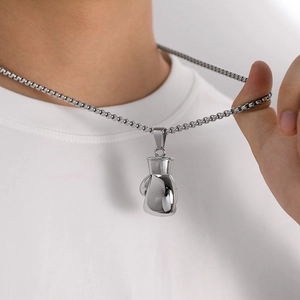 Close-up of polished silver boxing glove pendant on a box chain worn on white t-shirt