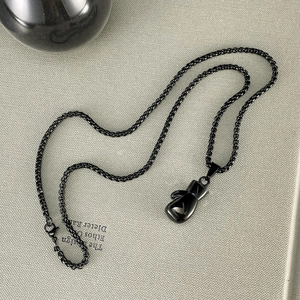 Detailed close-up of a high-shine black boxing glove pendant on a matching chain