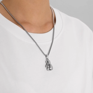 Close-up of polished silver boxing glove pendant with a box chain on a white sweatshirt