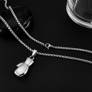 Macro view of boxing glove pendant with silver box chain on dark textured background