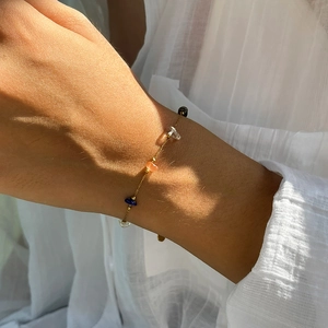 Delicato bracciale a catena dorata con pietre naturali colorate al polso al sole