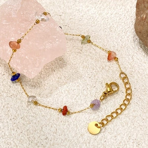 Dettaglio di pietre naturali colorate su bracciale a catena dorata con chiusura a moschettone
