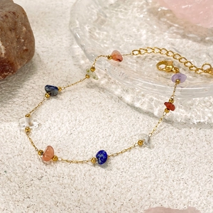 Dettaglio macro del bracciale a catena dorata con pietre naturali colorate e chiusura a moschettone