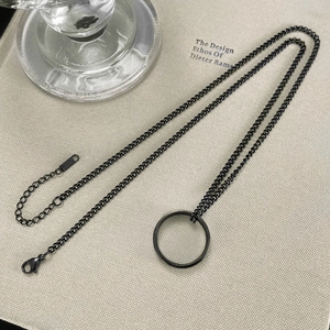 Detail shot of minimalist black titanium crown necklace with ring pendant on fabric
