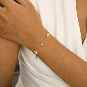 Close-up of golden stainless steel bracelet with zircon flower charms on model wrist