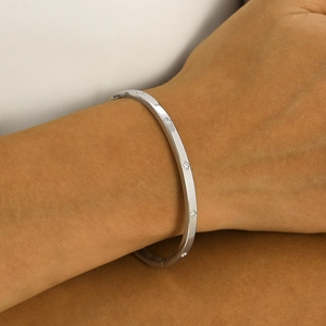 Close-up of silver stainless steel bangle with clover motifs and zircon stones on wrist
