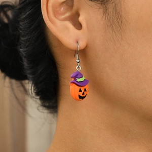 Close-up of Halloween pumpkin earrings with purple wizard hats on a female model