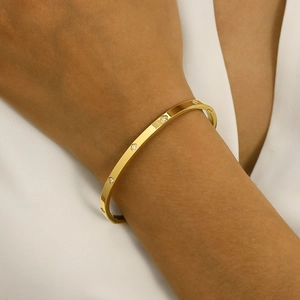 Close-up of gold stainless steel bangle with zircon star-shaped engravings on a wrist
