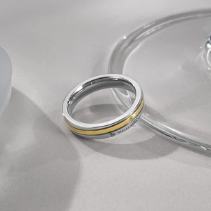Détail de bague en acier bicolore avec insert doré, diamant unique et gravure script