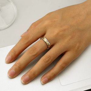 Gros plan d'une bague bicolore en acier inoxydable avec gravure et un zircon incrusté