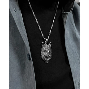 Detail van een wolfskop hanger aan een dikke stalen ketting gedragen op casual kleding