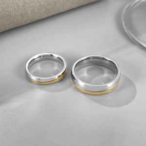 Gros plan des bagues de couple en acier poli avec insert doré et fini miroir