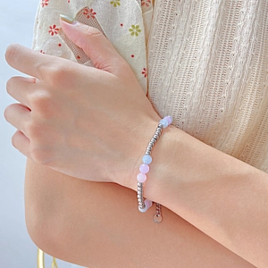 Detail of beaded bracelet with natural pastel stones and stainless steel charms on wrist