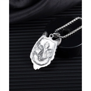 Detailopname van een zilveren wolfskop hanger in punkstijl met een boxketting op donkere basis