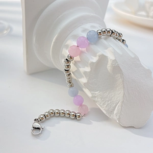 Detailed shot of beaded bracelet with pink and blue natural stones on a Roman pillar