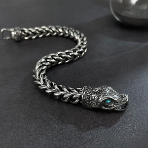 Detail of snake head metal bracelet with blue stone eyes and woven chain texture