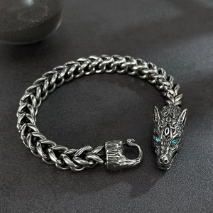 Macro shot of silver wolf head bracelet with blue stone eyes and thick metal links