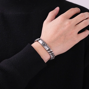 Nahaufnahme eines silbernen Löwenkopf-Reliefs an einem groben Panzerarmband für Herren