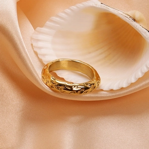 Macro detail of gold-plated stainless steel ring with hammered texture on pink silk background