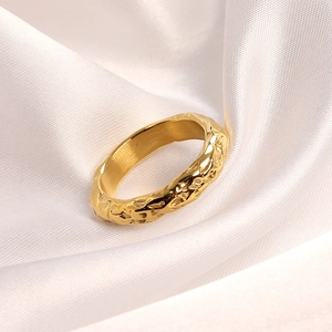 Macro detail of the golden hammered texture and irregular lava design on the steel ring
