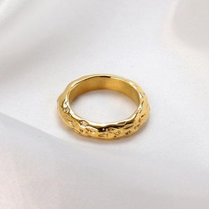 Hammered texture gold stainless steel ring on white silk background from top view