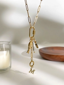 Detail van paperclipketting met gouden vis, barokke parel en bedel met letter M