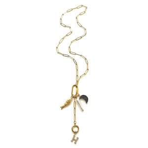 Detail van gouden paperclip ketting met vis, maan en strass letter H hangers