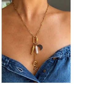 Gouden paperclip ketting met barokparel, maan en vis bedeltjes gedragen door een model