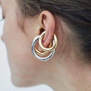 Nahaufnahme der minimalistischen Triple-Hoop-Ohrmanschette in Gold und Silber poliert