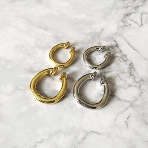 Minimalistische Ear Cuffs in Gold und Silber auf weißem Marmorhintergrund