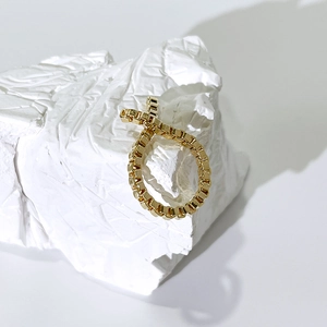 Detailaufnahme eines goldenen Box-Ketten-Rings auf weißem strukturiertem Stein